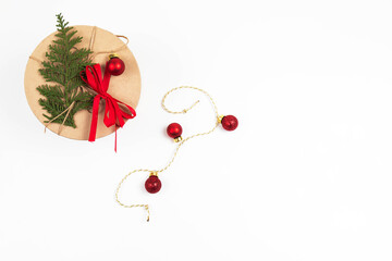 Round craft box for Christmas gifts with a small Christmas tree and red garland balls. White background,