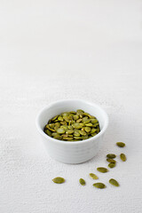 Side view of roasted pumpkin seeds in white bowl. Dry Pepita after shelling on white background. Copy space
