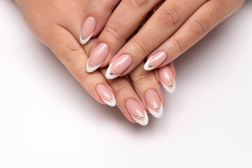 Gel manicure with crystals, stones on all nails. French white sharp manicure on long sharp nails close-up on a white background.