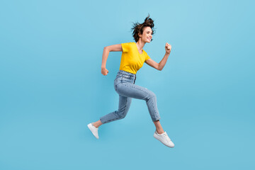 Fototapeta na wymiar Full length profile photo of young lady jump run wear yellow t-shirt jeans sneakers isolated blue color background