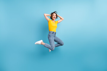 Full length photo of funny lady jump arms head open mouth wear yellow t-shirt jeans sneakers isolated blue color background