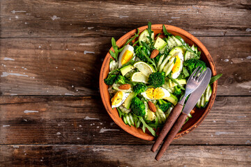 Green salad with avocado, cucumber, broccoli and egg. Healthy organic vegan salat with sliced avocado pear. Top view. Copy space