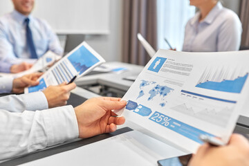 people and corporate concept - close up of happy business team with papers meeting at office