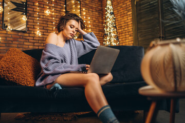 Pretty young brunette at home on the couch using laptop