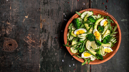 Healthy avocado salad broccoli, cucumber, arugula, lime and egg. Top view. Free space for your text