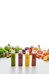 Composition of healthy detox juices and smoothies in bottles with paper straws, Various colorful fruits and vegetables isolated over white background