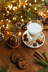 Glass of fresh milk and stack of chocolate chip cookies arranged on wooden table at home for Santa Claus on Christmas Day 