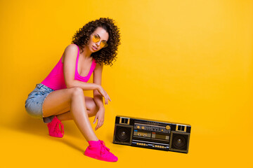 Full length profile photo of tender gorgeous lady party summer chill posing near old fashion vintage boom box wear sun specs pink singlet skirt sneakers isolated shine yellow color background