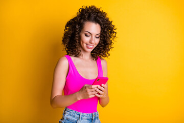 Photo of funny charming lady summer weekend good mood telephone write blog post millennial vacation chill popular places wear pink singlet isolated shine yellow color background
