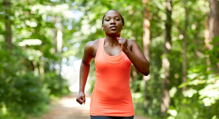 fitness, sport and healthy lifestyle concept - young african american woman running in forest