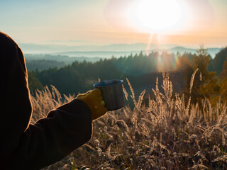 girl hold mug of tea in mountains Beskides in November in sunset