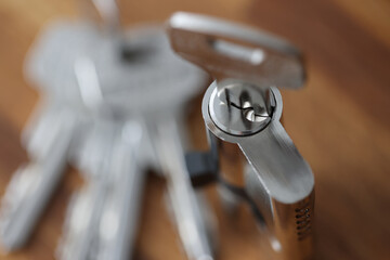 Steel key in keyhole lying on wooden table closeup. Reliable property protection concept.