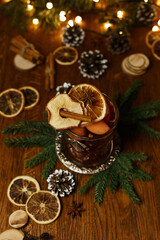 Glass of delicious mulled wine garnished with dried fruits and cinnamon stick arranged on table in...