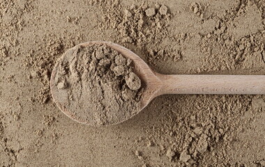 Organic linseed protein powder pile with wooden spoon background and texture