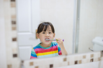 young girl brushing teeth by herself  in bathroom