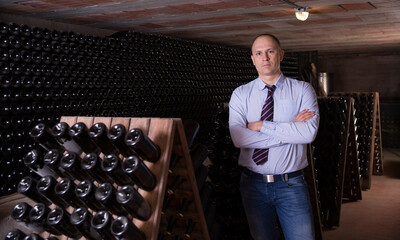 Confident succesful man winemaker posing in own winery vault