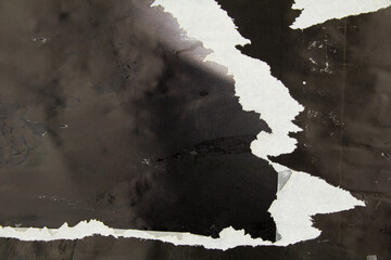 Old black torn and crumpled magazine paper with dirty glue marks and stains. Abstract background.
