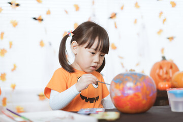 young girl painting pumpkin for halloween party at home