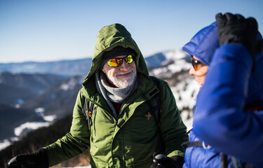 Fototapeta na wymiar Senior couple hikers talking in snow-covered winter nature.