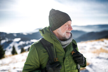 Portrait of senior man standing in snow-covered winter nature.