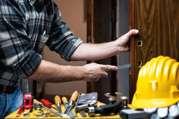 Carpenter at work repairs and installs the door lock. Carpentry.