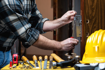 Carpenter at work repairs and installs the door lock. Carpentry.