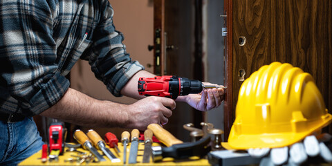 Carpenter at work repairs and installs the door lock. Carpentry.