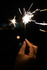 Cropped Hand Holding Sparkler At Night