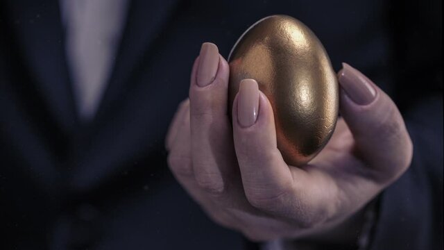 golden chicken egg in female hand,business concept