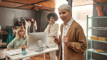 A close up of a white mature well-dressed ladyboss with a short haircut addressing her collaborateurs