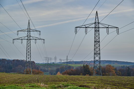 Large transmission towers in the countryside. Different types of electricity pylons in the countryside. Large electricity poles in an autumn landscape.