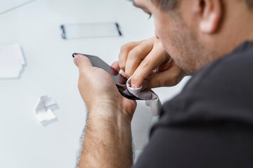 a man changes the protective glass on a smartphone