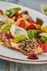grilled chicken with sesame next to grilled vegetables on wooden table