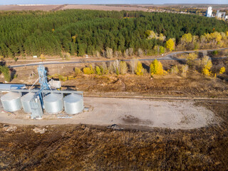 Aerial drone view modern steel agricultural grain granary silos cereal storage warehouse loading cargo grain carrier sunset. Agribuisness farmland rural industry landscape scene. Mill store facility