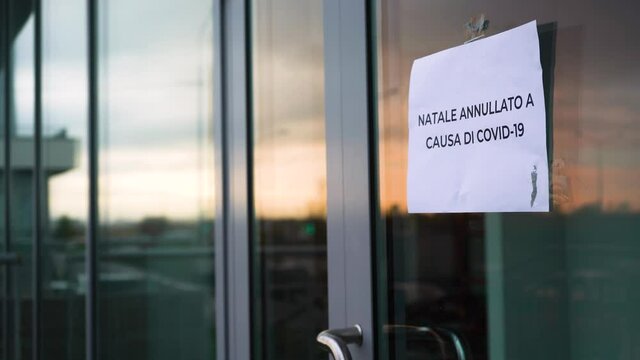 Shop owner hangs "Natale annullato a causa di covid-19" sign on glass door during pandemic covid-19 coronavirus quarantine. Business suffered financial losses.