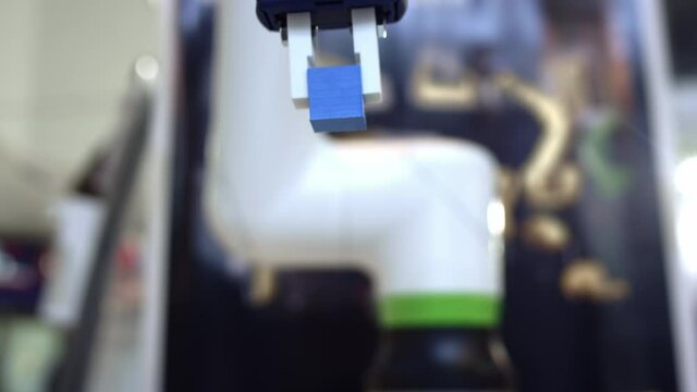 Futuristic robot hand picks up and moves colored cubes, artificial intelligence controls the robot's motor skills