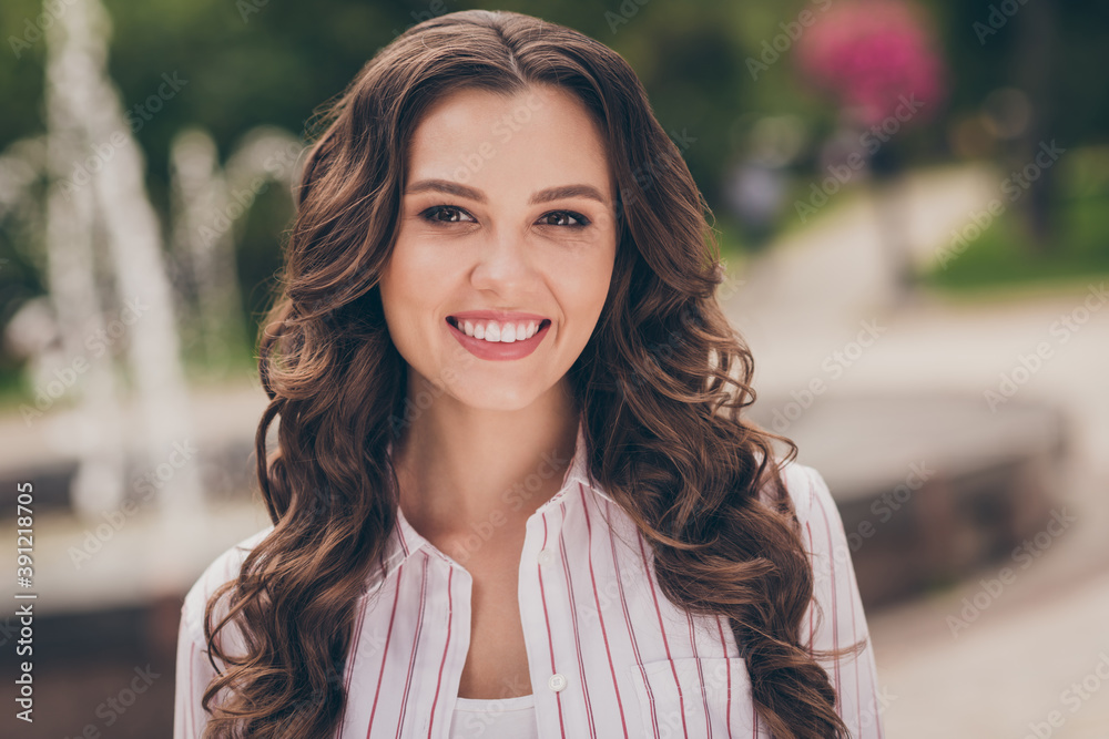 Sticker Photo portrait of nice girl with long curly hair walking in the city wearing white casual striped shirt smiling