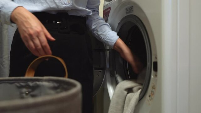 Woman loading clothes into washing machine.