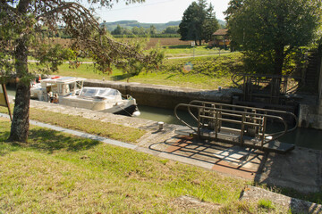 Un bateau de plaisance arrive dans une écluse du Canal Latéral à la Garonne et va attendre patiemment que l'eau descende pour franchir les portes et continuer sa route