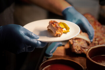 close up hand serve cutting barbecue rack on plate