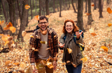 Two young hikers with backpack walking in forest.