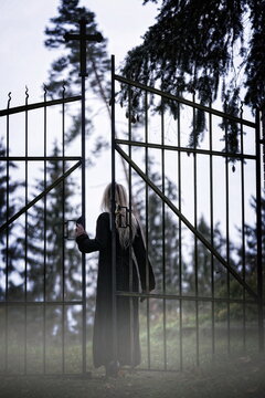 Blonde woman entering the gate of an cemetery