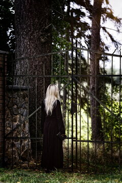 Blonde woman standing in front of a cemetery gate