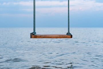 Wooden swing with ropes overlooking the sea. Swing on seashore. Dream vacation