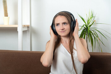 Girl at home with headphones listening to music, audiobook podcasts.