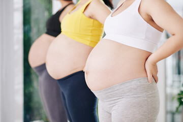 Cropped image of pregnant women standing in row after attending yoga class in health club