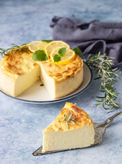 Lemon vanilla cheesecake decorated with rosemary, mint and lemon slices. Ricotta no crust cheesecake or casserole. Blue background.