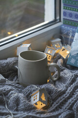 Fototapeta na wymiar Christmas gifts and garlands ,cup of hot drink on knitted grey blanket