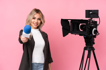 Reporter woman holding a microphone and reporting news over isolated pink background
