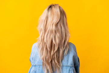 Fototapeta premium Young Russian woman isolated on yellow background in back position